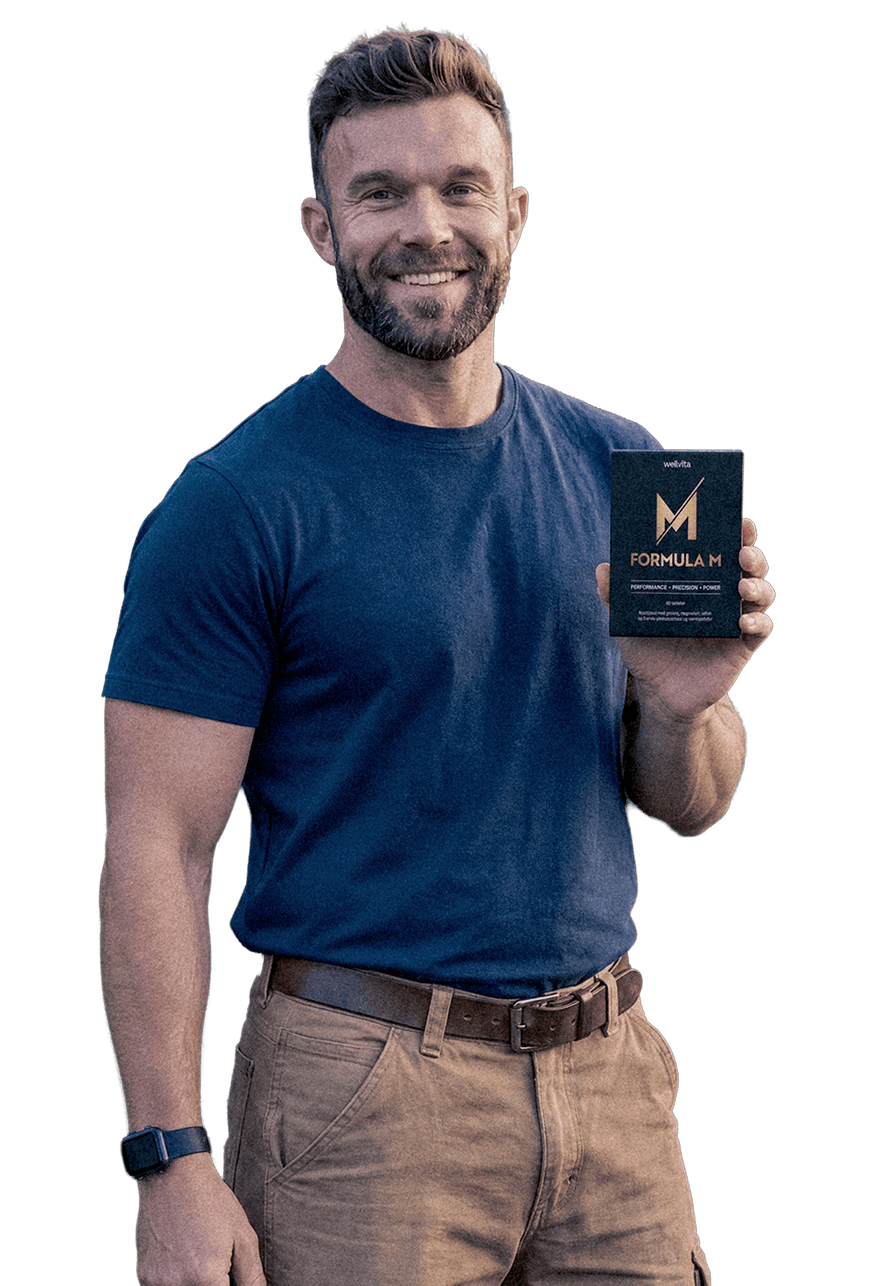 A smiling man in a navy blue t-shirt and khaki pants holds up a black box of Formula M on a solid white background.