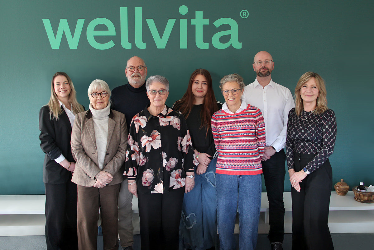 Group of people standing in front of a wellvita branded background